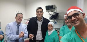 A group of people gathered together in a room at the Nazareth Hospital, Tamer Hidari is wearing Santa hats.