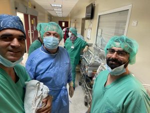 A photo of Tamer Hidari with nurses and a surgeon wearing scrubs, hats and masks, ready to enter the Operating Rooms at the Nazareth Hospital.